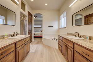 Ensuite bathroom with wood finished floors, a garden tub, two vanities, a shower with shower curtain, and recessed lighting