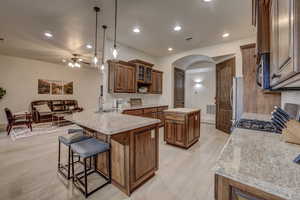 Kitchen featuring stainless steel appliances, arched walkways, a peninsula, a breakfast bar area, and a ceiling fan
