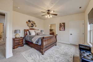 Bedroom featuring light colored carpet, ensuite bath, and ceiling fan