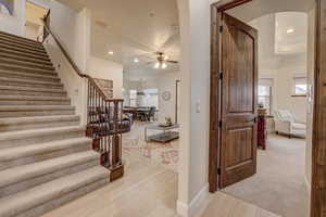 Staircase featuring arched walkways, a ceiling fan, wood finished floors, recessed lighting, and plenty of natural light