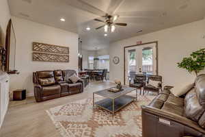 Living room with ceiling fan, light wood-style flooring, recessed lighting, and french doors