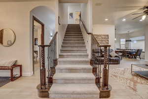 Staircase featuring ceiling fan, wood finished floors, recessed lighting, and arched walkways