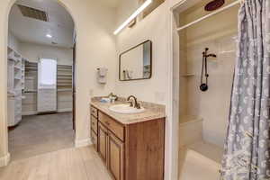 Bathroom with vanity, a walk in closet, curtained shower, and wood finished floors
