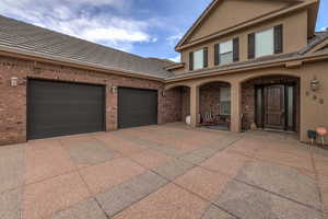 View of front of property featuring brick siding, driveway, covered porch, and stucco siding