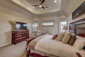 Bedroom with light carpet, a tray ceiling, a ceiling fan, and recessed lighting