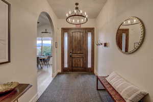 Foyer entrance featuring a chandelier, arched walkways, and lofted ceiling
