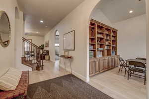 Entryway with light wood finished floors, arched walkways, recessed lighting, and stairway