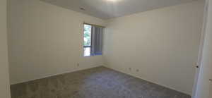 Empty room featuring dark carpet and baseboards