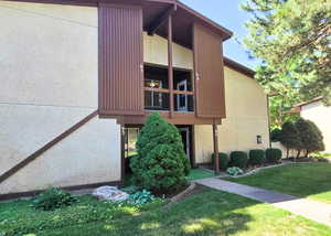 View of home's exterior featuring a balcony, a yard, and stucco siding