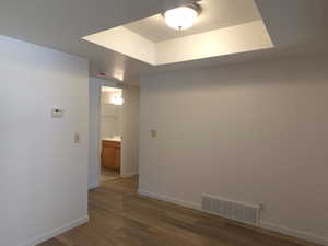 Corridor featuring light wood-style flooring and a tray ceiling