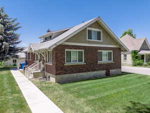 View of Front of home and front entrance door to upper duplex, with brick siding, a lawn, and a chimney