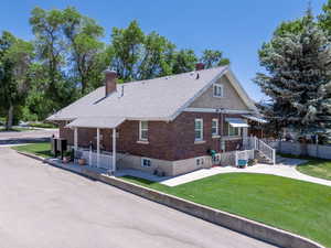 View of side of home with a lower entrance, chimney, brick siding, and roof with shingles