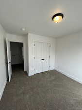 Five plex Unfurnished bedroom with dark carpet and a closet