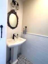 Bathroom featuring tile patterned flooring, tile walls, and a wainscoted wall