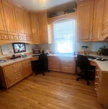 Office with built in desk and light wood-style floors