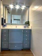 Bathroom with vanity, wood finished floors, and wooden walls