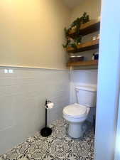 Bathroom featuring tile walls, a wainscoted wall, and tile patterned flooring