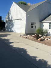 View of property exterior with roof with shingles, a garage, and driveway