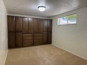 Unfurnished bedroom featuring a textured ceiling and light colored carpet
