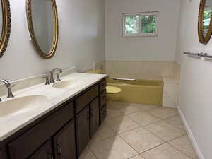 Full bath featuring double vanity, a garden tub, and tile patterned flooring