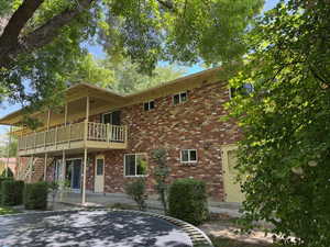 Rear view of house featuring brick siding, a patio, stairs, and a deck