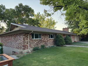 View of side of home featuring a lawn, a chimney, and brick siding