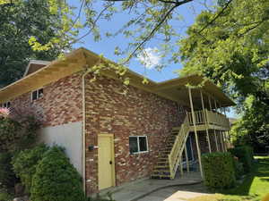 Back of property featuring brick siding, stairway, and a patio area