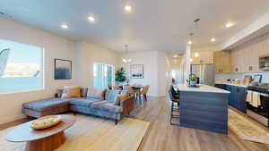 Living room featuring light wood-style flooring, a chandelier, and recessed lighting