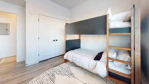 Bedroom featuring electric panel, wood finished floors, and a closet