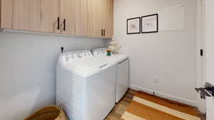 Laundry room with cabinet space, separate washer and dryer, and light wood-type flooring