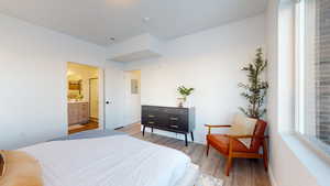 Bedroom featuring light wood-type flooring, electric panel, and ensuite bath