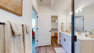Full bath with wood finished floors, vanity, and a walk in closet