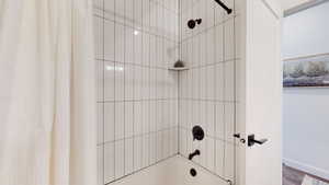 Bathroom featuring shower / bath combo and wood finished floors