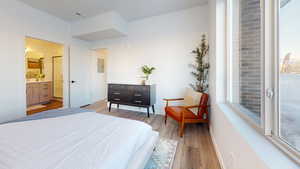 Bedroom with light wood-style flooring, electric panel, and multiple windows