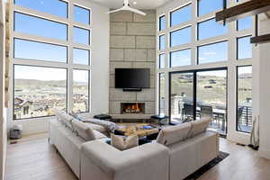 Living room with a towering ceiling, a lit fireplace, and light wood-style floors
