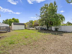 Fenced backyard featuring a shed and a deck