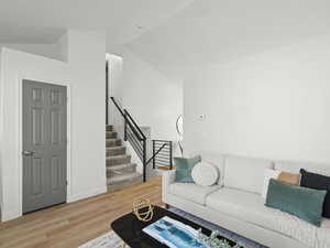 Living area with wood finished floors, stairway, and lofted ceiling