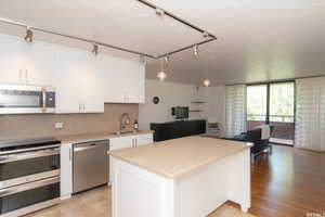 Kitchen featuring appliances with stainless steel finishes, open floor plan, a kitchen island, and white cabinetry