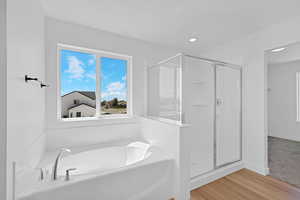Full bath featuring a shower stall, light wood-type flooring, a garden tub, and recessed lighting