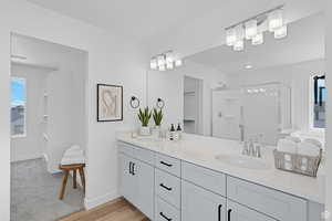 Bathroom featuring double vanity, a shower stall, and light wood-type flooring