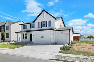 Modern farmhouse featuring covered porch, concrete driveway, a garage, and board and batten siding