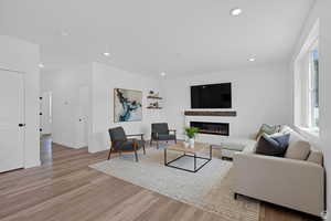 Living room with a glass covered fireplace, recessed lighting, and light wood finished floors