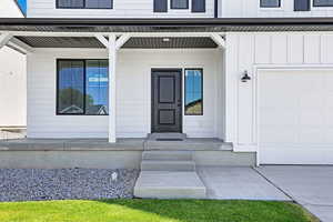 Doorway to property featuring a garage, a porch, and board and batten siding