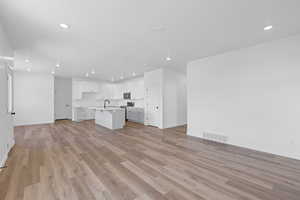 Unfurnished living room featuring light wood-type flooring and recessed lighting