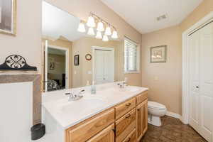 Ensuite bathroom featuring a closet, double vanity, and tile patterned floors