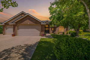 View of front facade with concrete driveway, brick siding, an attached garage, and a front yard