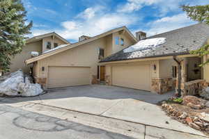 View of front of house featuring stone siding, a garage, and concrete driveway