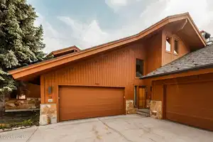 Rustic home featuring stone siding, driveway, a garage, and board and batten siding