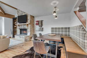 Dining space featuring wood finished floors, a fireplace, and beamed ceiling