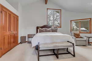 Bedroom with light colored carpet and lofted ceiling